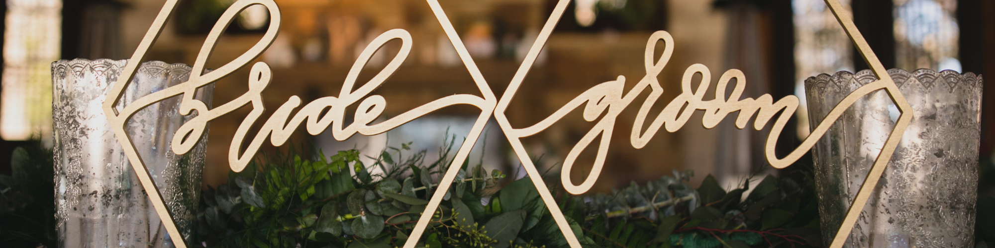 bride and groom signs on a wedding table with greenery 